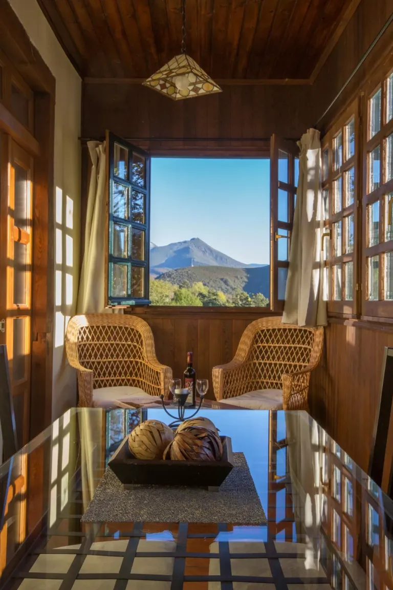 Mesa con sillas junto a una ventana con vistas a la naturaleza
